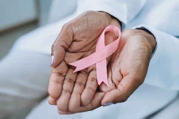 A pair of hands holds a pink breast cancer ribbon