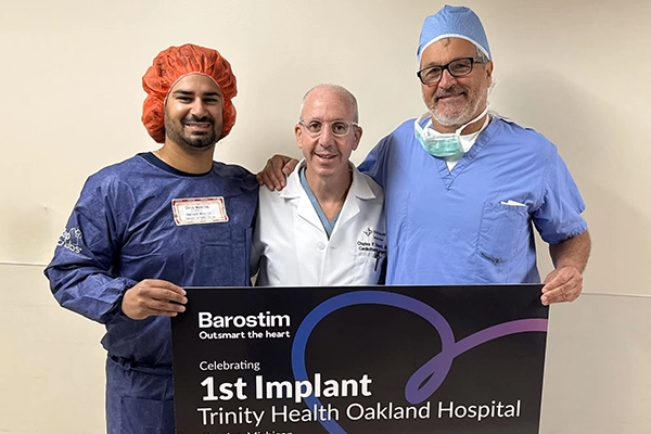 Three providers in scrubs stand next to each other with a sign that reads "1st Barostim Implant at Trinity Health Oakland Hospital"