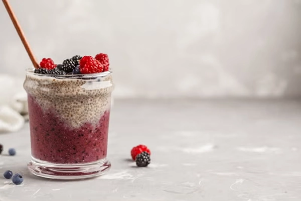 A mason jar full of chia pudding. It's topped with blueberries and raspberries.